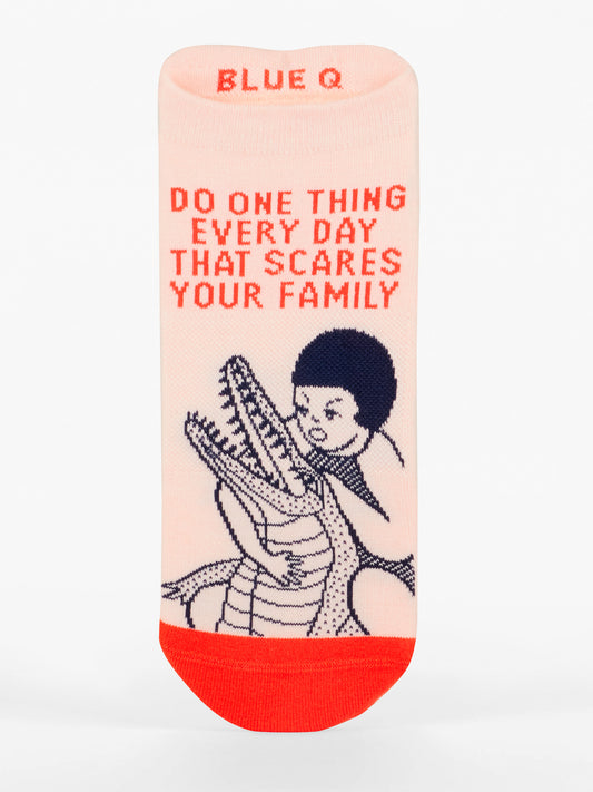 Blue Q's "Do One Thing Every Day That Scares Your Family" Sneaker Socks feature a cushioned single sock with red toe & top, an illustration of a child hugging an alligator, and the slogan in red. "BLUE Q" is printed at the top.