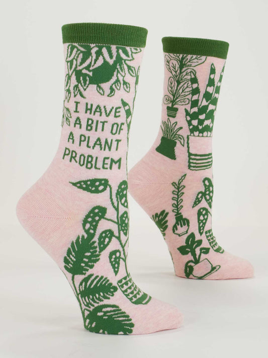 Blue Q "I Have A Bit Of A Plant Problem" Crew Socks feature pink combed cotton, green trim, playful monstera designs, and the fun phrase. Fits women's shoe size 5-10.