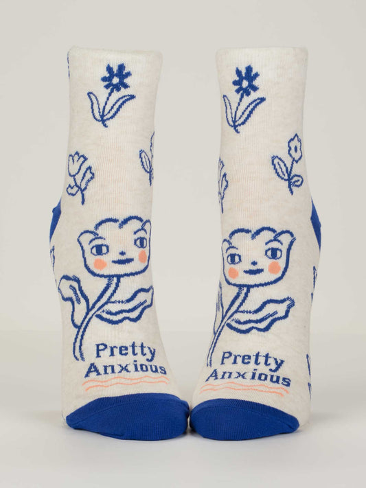 Blue Q’s Pretty Anxious Ankle Socks for women fit shoe size 5-10, are made from soft combed cotton, and feature blue toes and heels, a smiling blue flower with rosy cheeks, "Pretty Anxious" on the sole, and scattered blue flowers.
