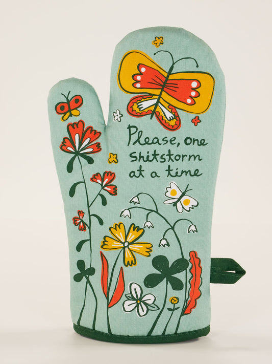 The Please, One Shitstorm At A Time Oven Mitt by Blue Q features colorful flowers, butterflies, and a cheeky phrase—ideal for tackling kitchen chaos one meal at a time.