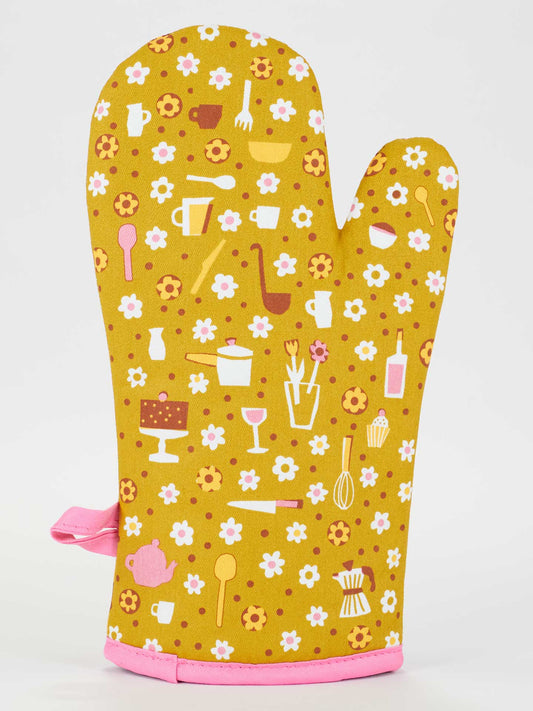 The Blue Q "No. I Will Never Want Your Help." oven mitt is super-insulated, yellow with a pink trim, decorated with white and pink flowers and kitchen images. Made from 100% cotton for comfort and durability.