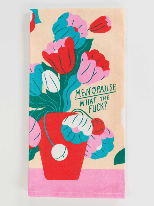 The Blue Q "Menopause. What The Fuck? Dish Towel" features a red vase with bold, stylized flowers in vibrant colors and playful green text, adding humor and color to kitchen organization or tackling any mess.