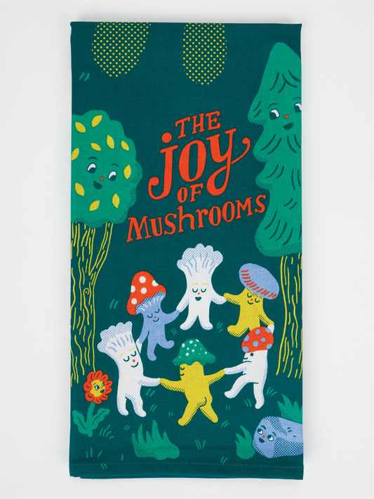 The Joy Of Mushrooms Dish Towel by Blue Q is a colorful tea towel made from super-absorbent, unbleached cotton. It features cheerful cartoon mushrooms holding hands in a ring and smiling, surrounded by trees, with "The Joy of Mushrooms" playfully written in red and yellow letters at the top.