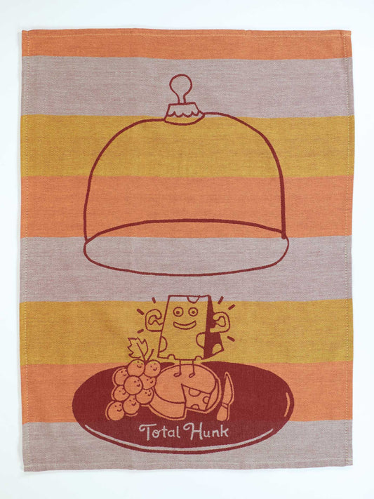 The Blue Q Total Hunk Dish Towel is a super-absorbent, unbleached cotton towel featuring a smiling cheese wedge under a glass dome with grapes, crackers, and charming orange, yellow, and beige stripes for playful kitchen style.