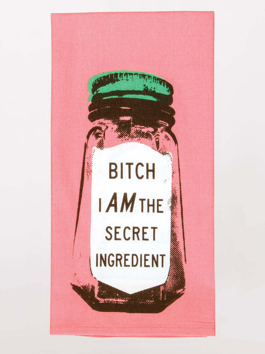 The Blue Q Bitch I Am The Secret Ingredient Dish Towel is a pink kitchen towel with a jar graphic and bold text, adding playful humor to your kitchen décor.