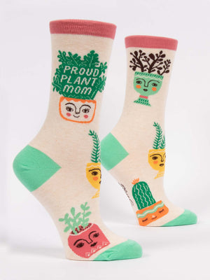 Blue Q’s Proud Plant Mom W-Crew Socks are beige with pink cuffs and green heels, made of soft combed cotton, and feature cheerful plant pot illustrations—including a Boston fern—and “Proud Plant Mom” text.