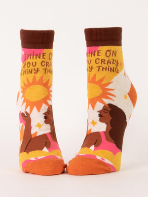 Blue Q's "Shine On You Crazy Shiny Thing" W-Ankle Socks feature a woman with dark hair basking in sunlight among flowers, crafted from a nylon-cotton blend and boldly printed with “Shine on you crazy shiny thing” across the tops.