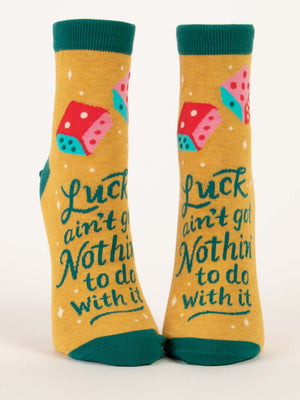 Blue Q’s Luck Ain't Got Nothin' To Do With It W-Ankle Socks feature a yellow combed cotton base with green cuffs, heels, and toes, colorful dice accents, and the bold phrase "Luck ain't got nothin' to do with it.