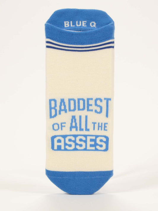 The Baddest Of All The Asses Sneaker Socks by Blue Q are cream-colored with blue toe, heel, and cuff. "BADDEST OF ALL THE ASSES" is boldly printed in blue, with Blue Q on the inner cuff and two thin blue stripes at the top.