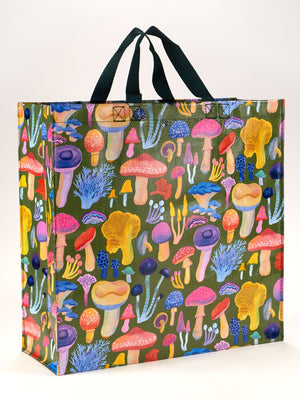 The Mushrooms Shopper by Blue Q is a reusable grocery bag with black handles, featuring a vibrant illustration of various mushrooms and fungi specimens on a green background.