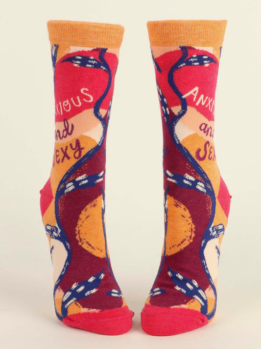 Blue Q’s Anxious and Sexy W-Crew Socks feature bold orange, red, and pink patterns with blue snakes and "anxious" and "sexy" written on them. This colorful combed cotton pair stands upright against a plain background.