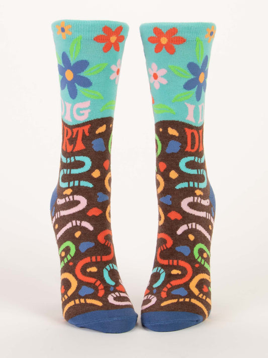 Blue Q’s I Dig Dirt W-Crew Socks feature bold blue and red petunias on turquoise, “I DIG DIRT” text, playful worms on soil-brown lower halves, and blue toes and heels—perfect for gardening lovers.