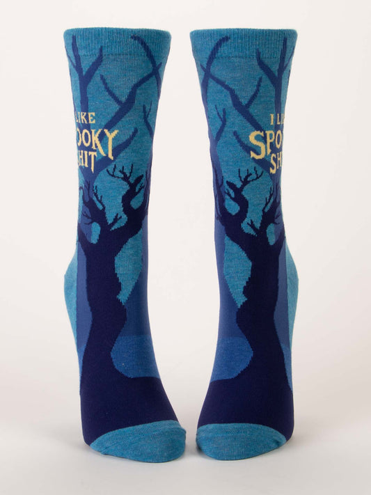 The Blue Q I Like Spooky Shit W-Crew Socks feature blue combed cotton with dark leafless tree silhouettes and yellow “I LIKE SPOOKY SHIT” text on a light background. Soft, comfortable, and perfect for any fan of spooky style.