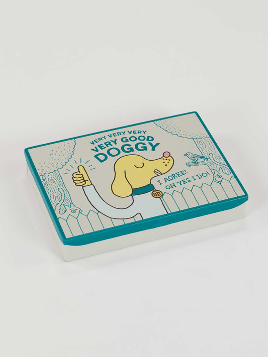 The Blue Q Very Very Very Very Good Doggy Pocket Box features a happy yellow dog giving a thumbs up beside "VERY VERY VERY VERY GOOD DOGGY" and a speech bubble on the lid saying "I AGREE! OH YES, I DO!"—a perfect pet gift.