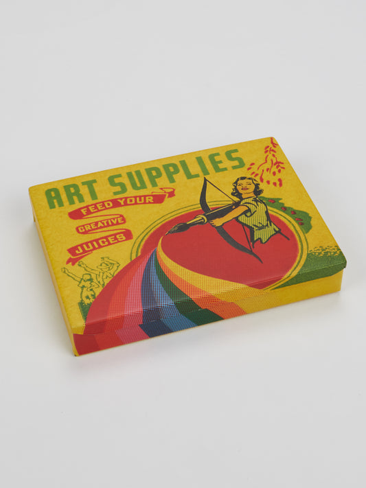A colorful, compact Art Supplies Pocket Box by Blue Q features retro-style artwork of a person shooting a bow to create a rainbow, with the phrase “Feed your creative juices” on a yellow background with red and green accents.