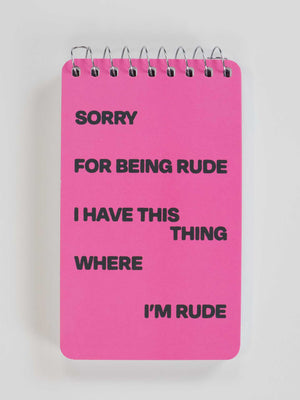 The Blue Q "Sorry For Being Rude. I Have This Thing Where I'm Rude" 3x5 pink spiral notebook features bold black text—perfect for quirky notes or keeping your thoughts organized in style!.