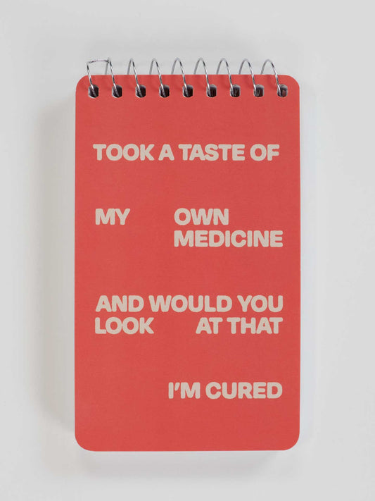 The Blue Q "Took A Taste Of My Own Medicine And Would You Look At That I'm Cured" 3x5 spiral notebook features a red cover with white text displaying the quirky phrase.