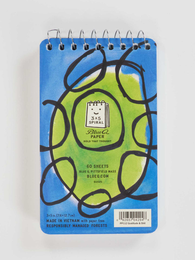 The Blue Q "Gratitude & Shit. Plus A Few Things That Piss Me Off" 3x5 spiral notebook has a blue-green abstract cover, center label, and 60 sheets—perfect for jotting down thoughts. Barcode at the bottom right corner.