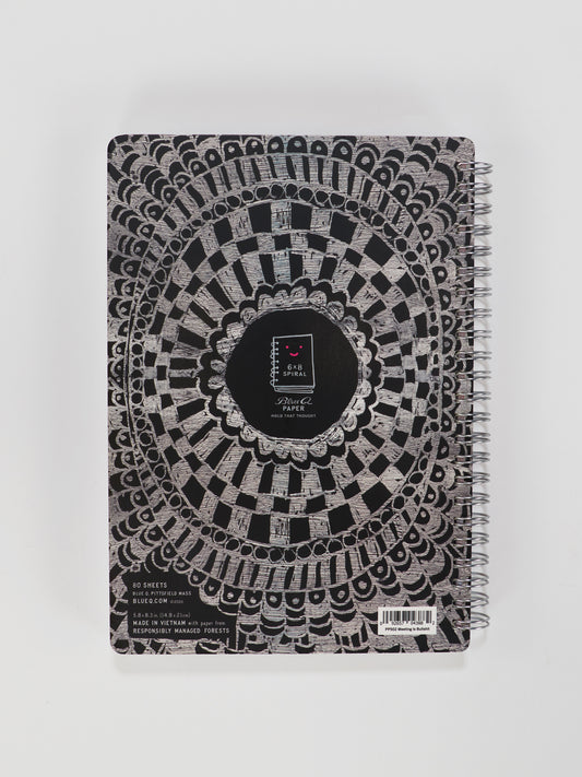 The Blue Q "This Meeting Is Bullshit" 6x8 Spiral Notebook features a black and silver geometric lace cover, a small rectangular center label, and a barcode at the bottom right—perfect for jotting down statements and observations.