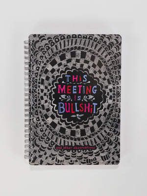 The Blue Q "This Meeting Is Bullshit" 6x8 Spiral Notebook features a black and silver patterned cover with the phrase in colorful letters and additional pink notes at the bottom.