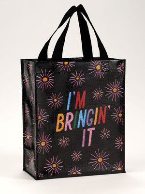 The I'm Bringin' It Handy Tote by Blue Q features sturdy black handles and a vibrant fireworks pattern with “IM BRINGIN IT” in bold, multicolored letters—perfect for carrying your essentials in colorful style.