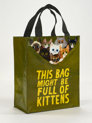 Blue Q’s “This Bag Might Be Full Of Kittens Handy Tote” is a green reusable bag with black handles, featuring illustrated kittens peeking over the top and a playful message on the front.