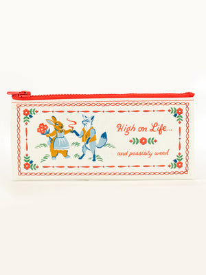The Blue Q "High On Life...And Possibly Weed" Pencil Case is a cream-colored, recycled zip pouch with red trim, featuring two cartoon foxes and playful text, plus decorative red and green accents.