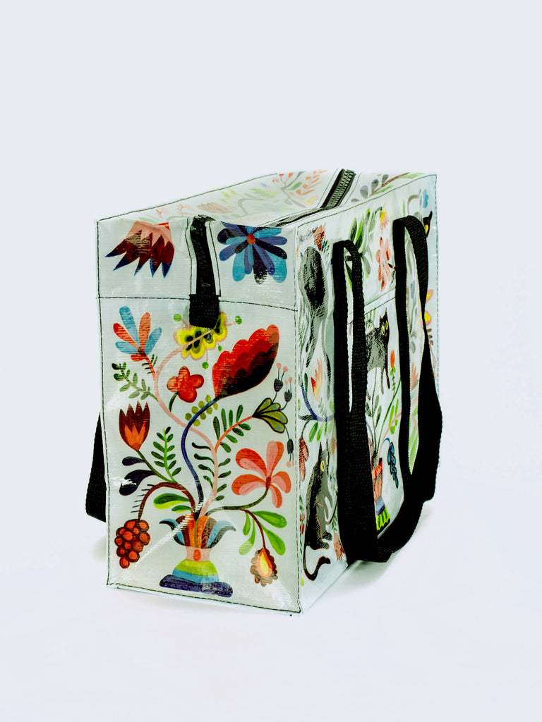 The Blue Q Here Kitty Shoulder Tote is a rectangular, reusable bag with black handles and colorful floral and leaf patterns—perfect as a stylish cat carrier or everyday pet tote.