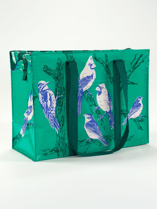 The Blue Q Songbird Shoulder Tote is a green reusable bag with dark green handles, featuring blue and white songbird illustrations perched on branches.