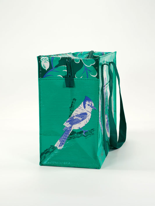 The Blue Q Songbird Shoulder Tote is a green reusable shopping bag with dark green handles, featuring a blue and white bird on a branch and leafy details. Ideal for bird lovers or anyone wanting stylish, eco-friendly accessories.