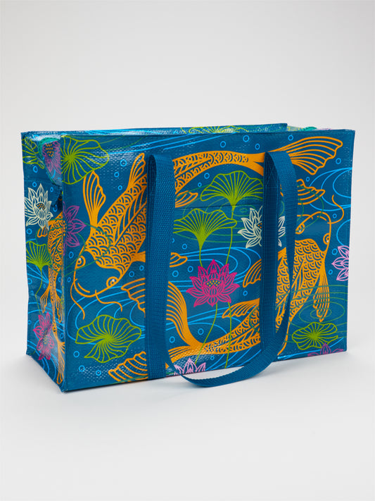 Introducing the Blue Q Koi Shoulder Tote—a reusable bag featuring sturdy blue handles, crafted from recycled materials and adorned with vibrant koi fish, lotus flowers, and lily pads on a serene blue background. Perfect for anyone who loves cheerful, nature-inspired designs.