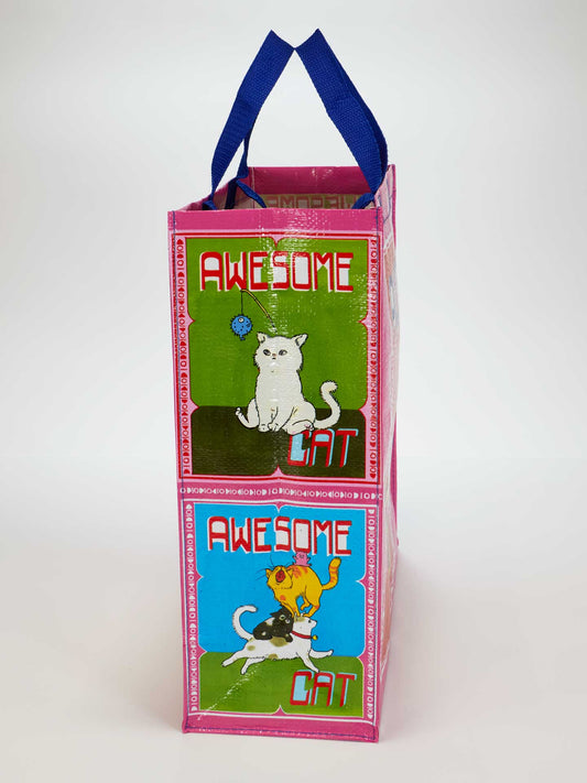 The Blue Q Awesome Cat Shopper is a pink tote with blue handles, cartoon cats, and “AWESOME CAT” text on both sides. Made from recycled material, it features playful cat designs on a green-blue background.
