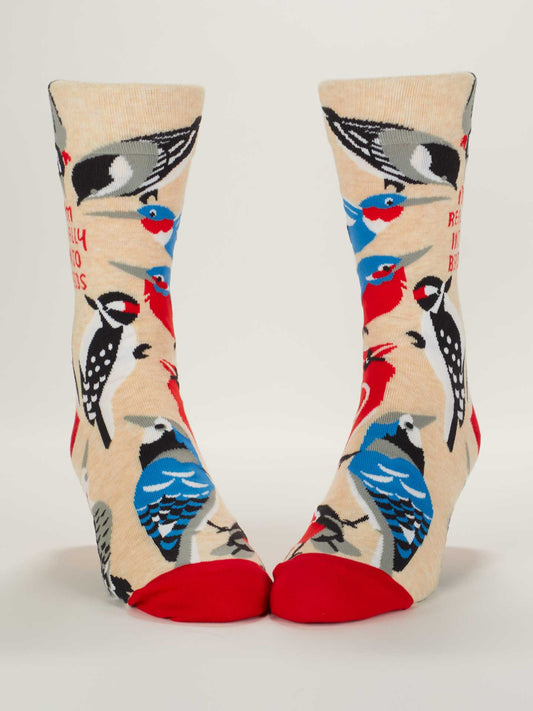 Blue Q’s “I’m Really Into Birds” M-Crew Socks feature a beige base with red toes, crafted from soft combed cotton and adorned with colorful cartoon birds in red, blue, black, and white for a playful touch.