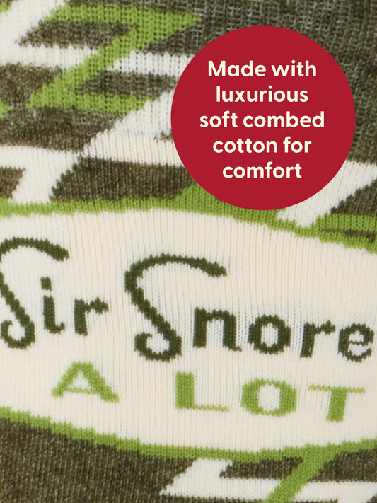 Close-up of green and white patterned fabric with text: Sir Snores A Lot. A red circle reads, Made with luxurious soft combed cotton for comfort by Blue Q, just like your favorite crew socks or earplugs for peaceful nights.