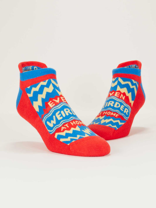 Blue Q's Even Weirder At Home Sneaker Socks are colorful ankle socks with red, blue, and yellow zigzag patterns, a soft heel tab for comfort, and "Even weirder at home" printed on them.