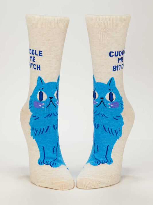 The Cuddle Me Bitch Crew Socks by Blue Q are cream-colored cotton socks featuring a blue cartoon cat with "Cuddle Me Bitch" printed above—ideal for fans of quirky cat socks.