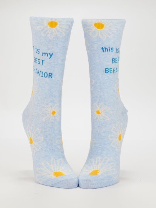 Blue Q’s "This Is My Best Behavior" Crew Socks for women (size 5-10) feature light blue combed cotton, white and yellow daisies, and bold blue text on the sides.