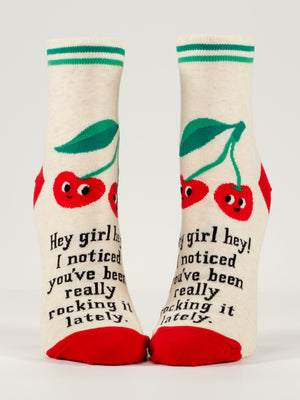 Blue Q's Hey Girl Hey! I Noticed You’ve Been Really Rocking It Lately W-Ankle Socks feature cream fabric with green stripes, red toes and heels, smiling faces, cherries, and a message—all in soft combed cotton.