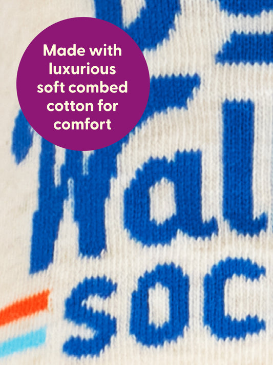 Close-up of fabric with blue text and a purple circle that reads, Made with luxurious soft combed cotton for comfort. The material appears soft and comfortable—perfect for Dog Walkin’ W-Ankle Socks by Blue Q or your favorite dog walking gear.