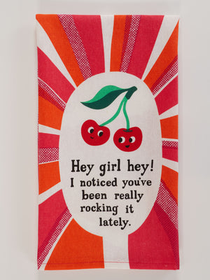 The Blue Q "Hey Girl Hey! I Noticed You've Been Really Rocking It Lately." dish towel features two cartoon cherries with faces and green leaves, surrounded by red and orange rays, plus the uplifting message: “Hey girl hey! I noticed you’ve been really rocking it lately.”.