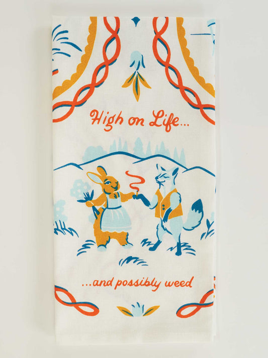 The Blue Q "High On Life...And Possibly Weed" Dish Towel features an illustrated rabbit and fox standing, holding a joint, with playful text and blue, orange, and yellow tones—a fun decorative piece for your kitchen.
