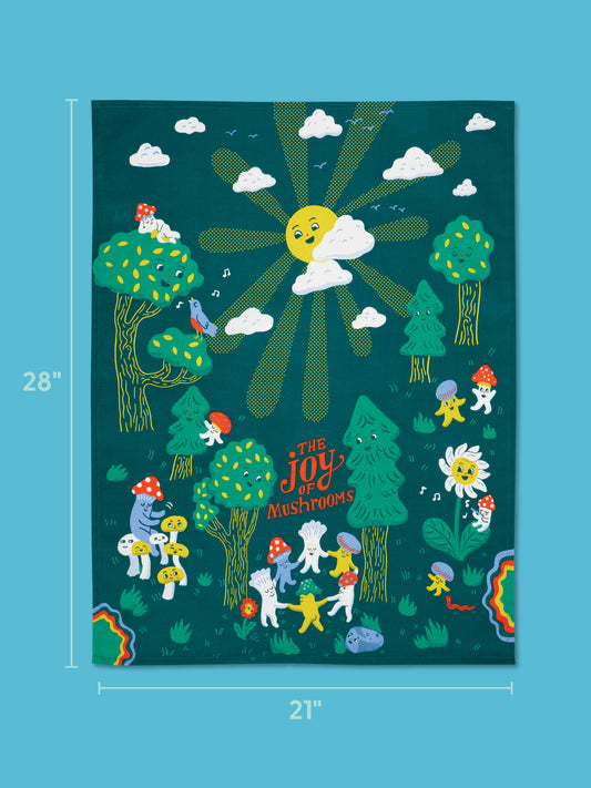 Brighten up your kitchen with the Blue Q "The Joy Of Mushrooms" Dish Towel, featuring a colorful illustration of mushrooms, trees, cheerful creatures, a smiling sun, and fluffy clouds on a dark teal background. Made from super-absorbent unbleached cotton and measuring 28 inches tall by 21 inches wide, this charming towel showcases the whimsical text "The Joy of Mushrooms.