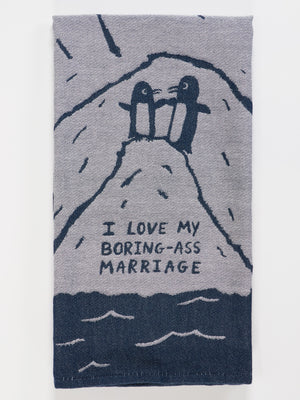 The Blue Q "I Love My Boring-Ass Marriage" dish towel features two penguins holding hands on a snowy hill, with the phrase "I LOVE MY BORING-ASS MARRIAGE" below them.