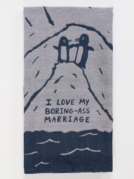 The Blue Q "I Love My Boring-Ass Marriage" dish towel features two penguins holding hands on a snowy hill, with the phrase "I LOVE MY BORING-ASS MARRIAGE" below them.