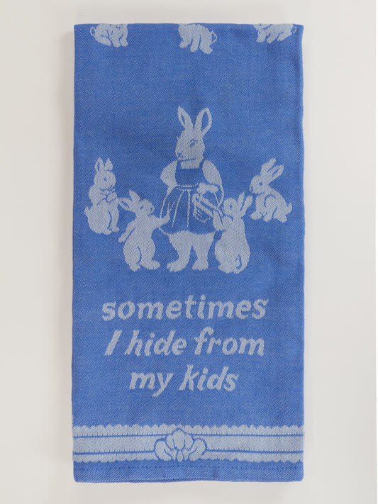 The Blue Q "Sometimes I Hide From My Kids Dish Towel" features super-absorbent unbleached cotton, blue color, white prints of a mother rabbit with five baby bunnies, and the humorous saying: “sometimes I hide from my kids.”.