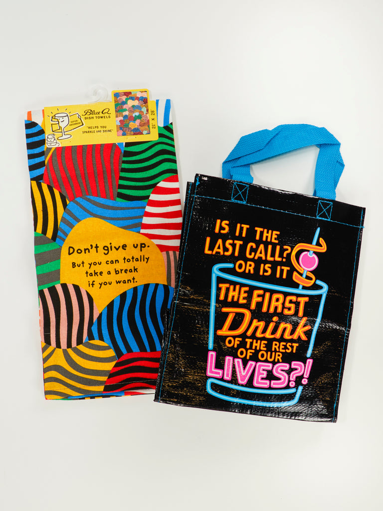 The Blue Q Take A Break Sale Pack includes a colorful striped dish towel with the text "Don’t give up. But you can totally take a break if you want." plus a black drink-themed gift bag—a cheerful bundle for anyone needing encouragement and style.