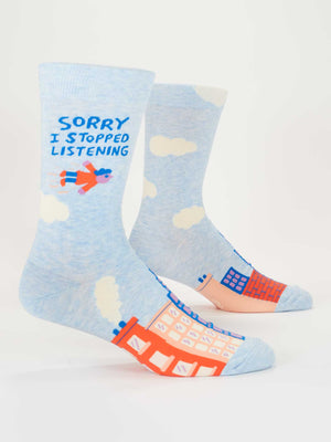 Blue Q’s Sorry I Stopped Listening M-Crew Socks (men's size 7-12) are light blue with white clouds, vibrant buildings, an orange and blue flying figure, and playful “SORRY I STOPPED LISTENING” text. Made from soft combed cotton.