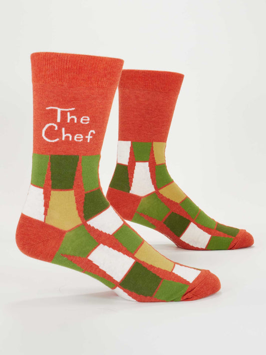 The Chef Men's Socks by Blue Q are red, soft combed cotton socks for men’s shoe sizes 7-12, featuring green, white, and gold geometric designs with "The Chef" in white near the top.